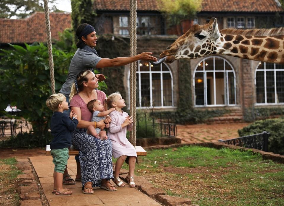 Garrett Gee y su familia fotografiados con una jirafa en Giraffe Manor en Kenia.